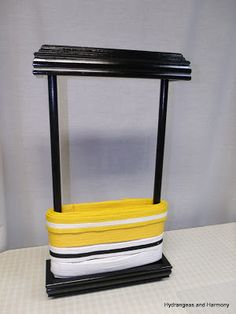 a yellow and white basket sitting on top of a black stand