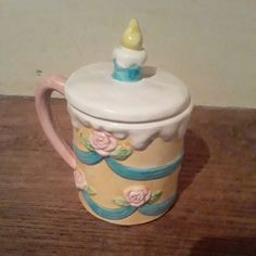 a ceramic tea pot with a candle on top sitting on a wooden table next to a wall