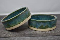 two green ceramic bowls sitting on top of a wooden table next to eachother