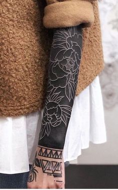 a woman's arm with tattoos on it and a flower tattoo on the arm