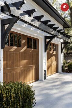 a white house with two brown garage doors and an awning over the front door