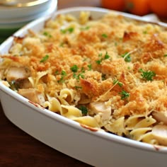 a casserole dish with chicken and pasta in it on a table next to oranges