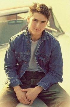 a young man sitting on top of a white car