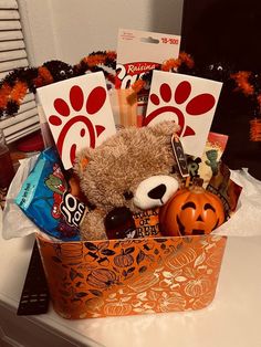 a teddy bear sitting in a basket filled with candy and candies on top of a counter