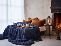 a living room with a fire place next to a bed and pillows on the floor