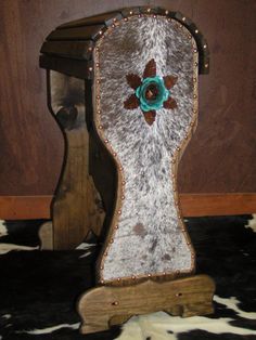 an old wooden chair with a flower on the back and cow hide rug underneath it