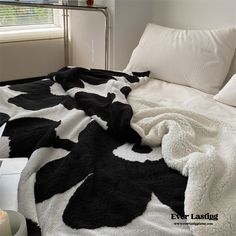 a black and white cow print blanket on a bed with two candles in front of it