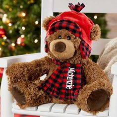 a brown teddy bear sitting on top of a white chair next to a christmas tree