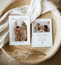 two christmas cards sitting on top of a wooden bowl next to a white blanket and a wood bowl