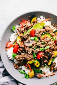 a close up of a plate of food with meat and vegetables on rice in it