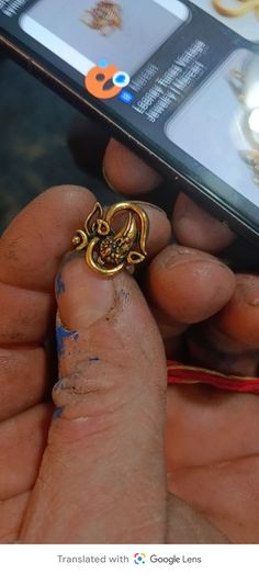 a person holding a cell phone in their hand with a gold ring on it's finger