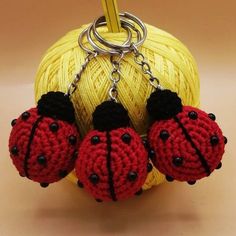 three crocheted ladybug keychains hanging from a ball of yarn