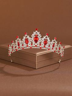 a red and white tiara sitting on top of a silver box next to a brown wall