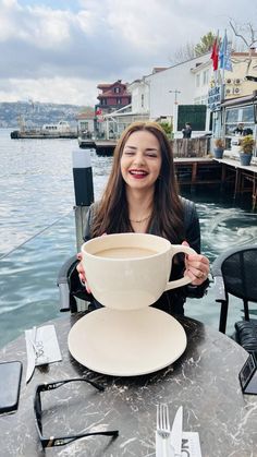 a woman sitting at a table with a cup of coffee