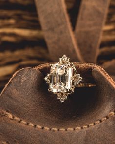 an old fashion ring is sitting on top of a brown leather bag