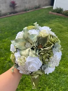 a bridal bouquet in the hand of someone holding it on their wedding day outside