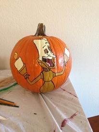 a painted pumpkin sitting on top of a table next to a pair of pencils