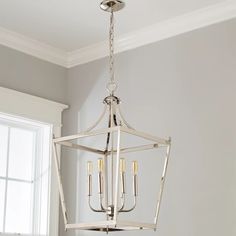 a chandelier hanging from the ceiling in a room with white walls and windows