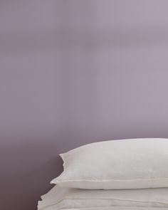 three pillows stacked on top of each other in front of a purple wall and floor