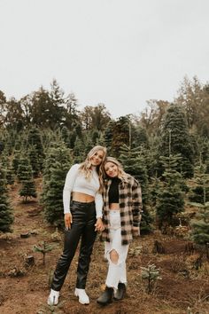 two women standing next to each other in the middle of a christmas tree farm field