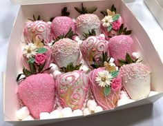 a box filled with pink and white decorated strawberries