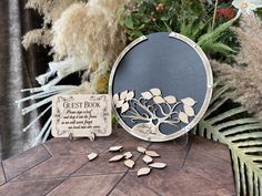 a table topped with lots of plants next to a plaque that says guest book and leaves