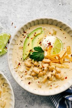 a bowl of soup with beans, avocado and sour cream on the side