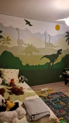 a child's bedroom with dinosaurs painted on the wall and stuffed animals laying on the bed