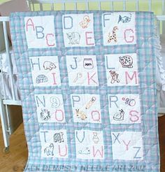 a baby crib with a blanket that has letters and animals on it