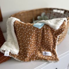 a brown and white polka dot blanket sitting on top of a wooden table next to a basket