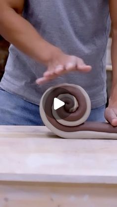 a man is making a chocolate donut on a table with the doughnut being rolled up