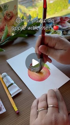 someone is painting an apple with watercolors