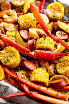 lobster, corn on the cob and carrots are cooked in an iron skillet