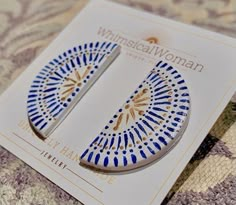 a pair of blue and gold earrings sitting on top of a card