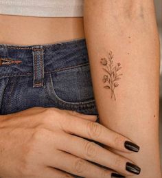 a woman's arm with a small flower tattoo on the left side of her body