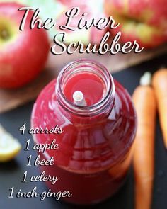 a jar filled with liquid sitting on top of a table next to apples and carrots