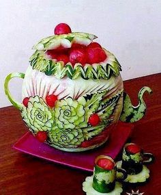 a watermelon carved teapot with fruits and vegetables in it