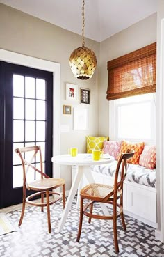 a dining room table with two chairs and a bench in front of the door that is open