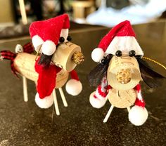 two wine corks with santa hats and bells on them are sitting on a table