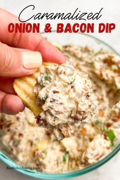 a hand holding a tortilla chip filled with onion and bacon dip in a glass bowl