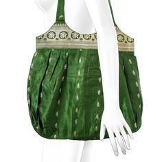 a mannequin wearing a green dress with gold trimmings and an open shoulder bag