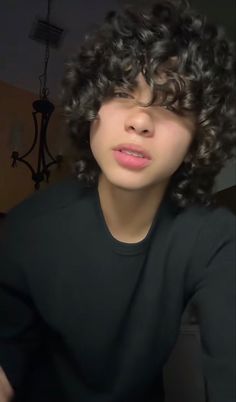 a young man with curly hair wearing a black shirt