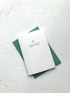 there is a white card with green envelopes on the table next to some papers