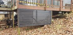 a wooden deck with metal slats on it and leaves covering the ground around it