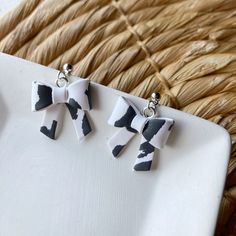 three pairs of black and white bow earrings sitting on top of a table next to a wicker basket