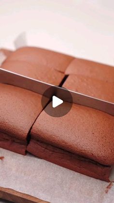 a knife cutting into some chocolate cake on a piece of parchment paper with the video below it