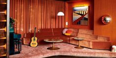 a living room with an orange couch and guitar on the table in front of it