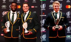 two men in suits and ties holding trophies