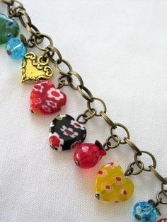 "This heart charm bracelet is made with multi-colored millefiori hearts, gold tone hearts, blue crystals, Czech faceted red glass and brass metals. It is adjustable along the chain from 7 to 8\". At random charms make each bracelet slightly different. This bracelet will be slipped into an organza bag and shipped in a bubble mailer." Heart-shaped Charms Beaded Bracelets For Jewelry Making, Multicolor Heart Charm Bracelet, Valentine's Day Multicolor Heart Beads Jewelry, Multicolor Jewelry With Heart Charm And Round Beads, Adjustable Multicolor Charm Bracelet With Heart Beads, Adjustable Multicolor Heart-shaped Jewelry, Multicolor Heart Bracelet For Valentine's Day, Multicolor Charm Bracelet With Heart Beads, Multicolor Charm Bracelet With Heart-shaped Beads