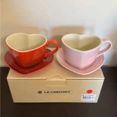 two cups and saucers sitting on top of a cardboard box next to each other